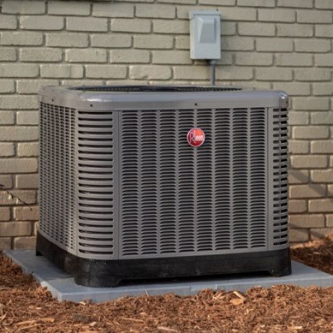 A rheem air conditioner is sitting outside of a brick building