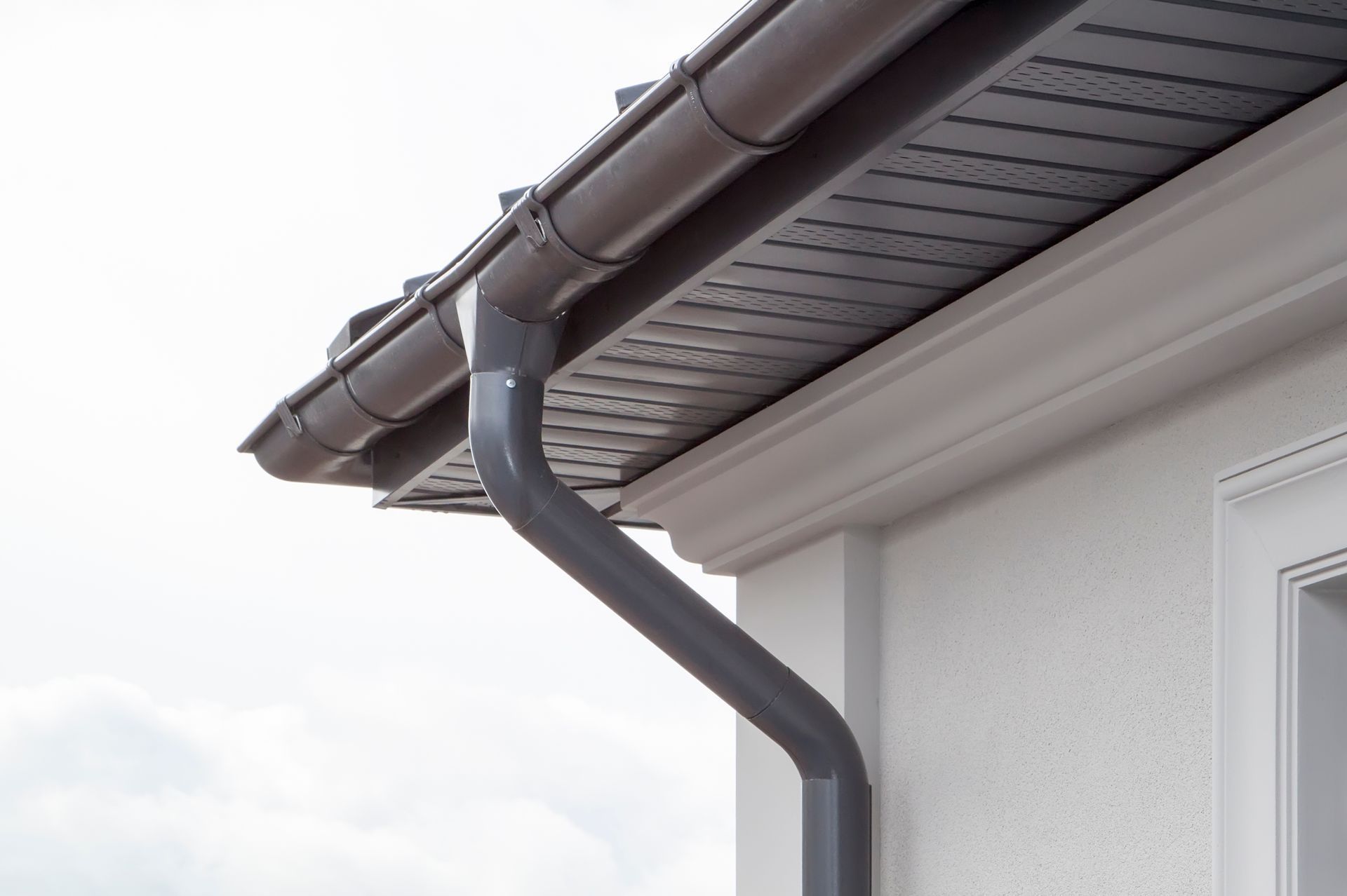 A close up of a gutter on the side of a house.