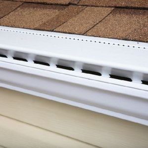 A white gutter is attached to the side of a house.