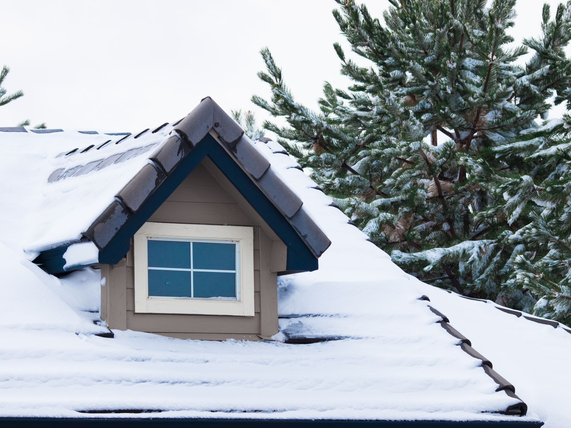 A snowy roof with a small window on it