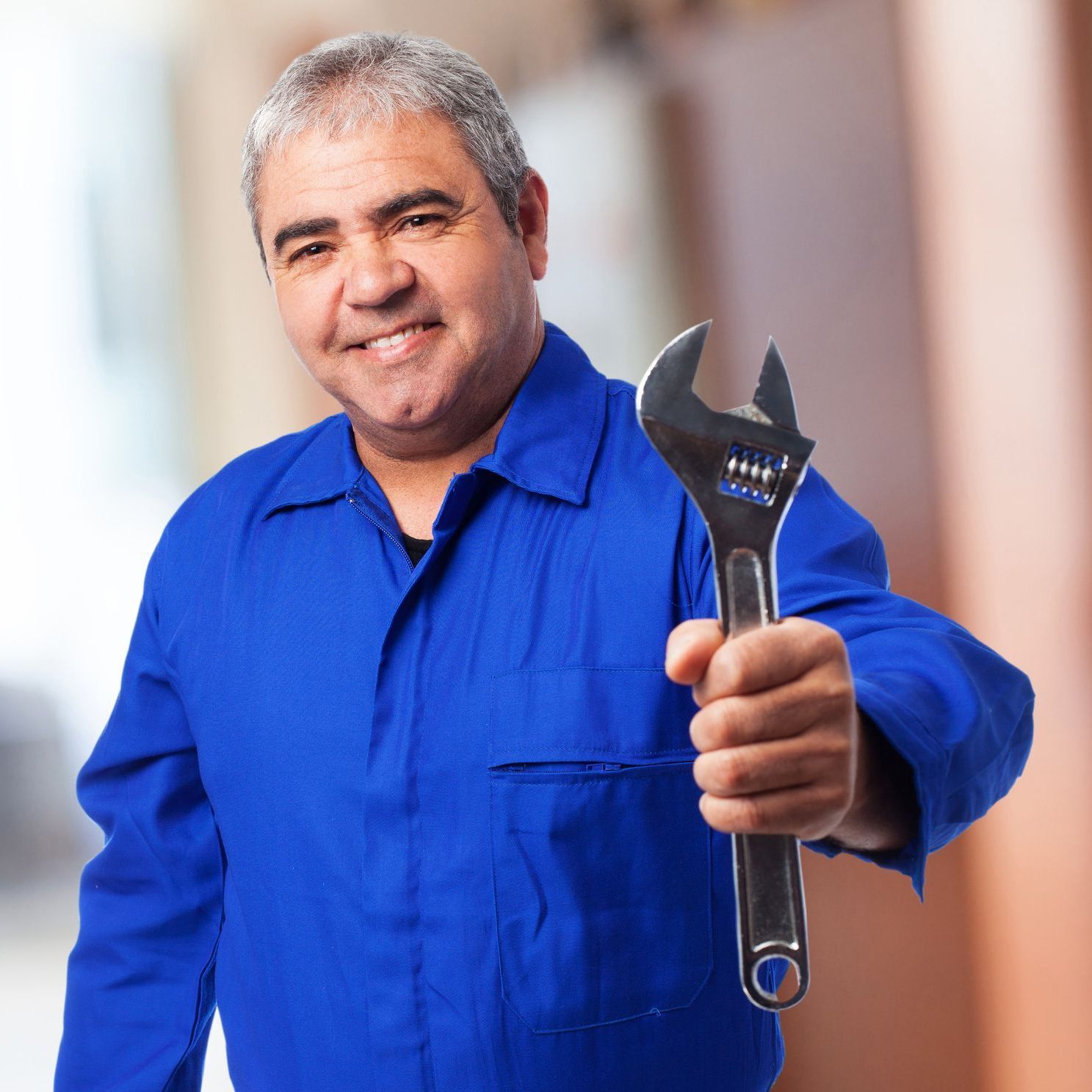 A man in a blue shirt is holding a wrench