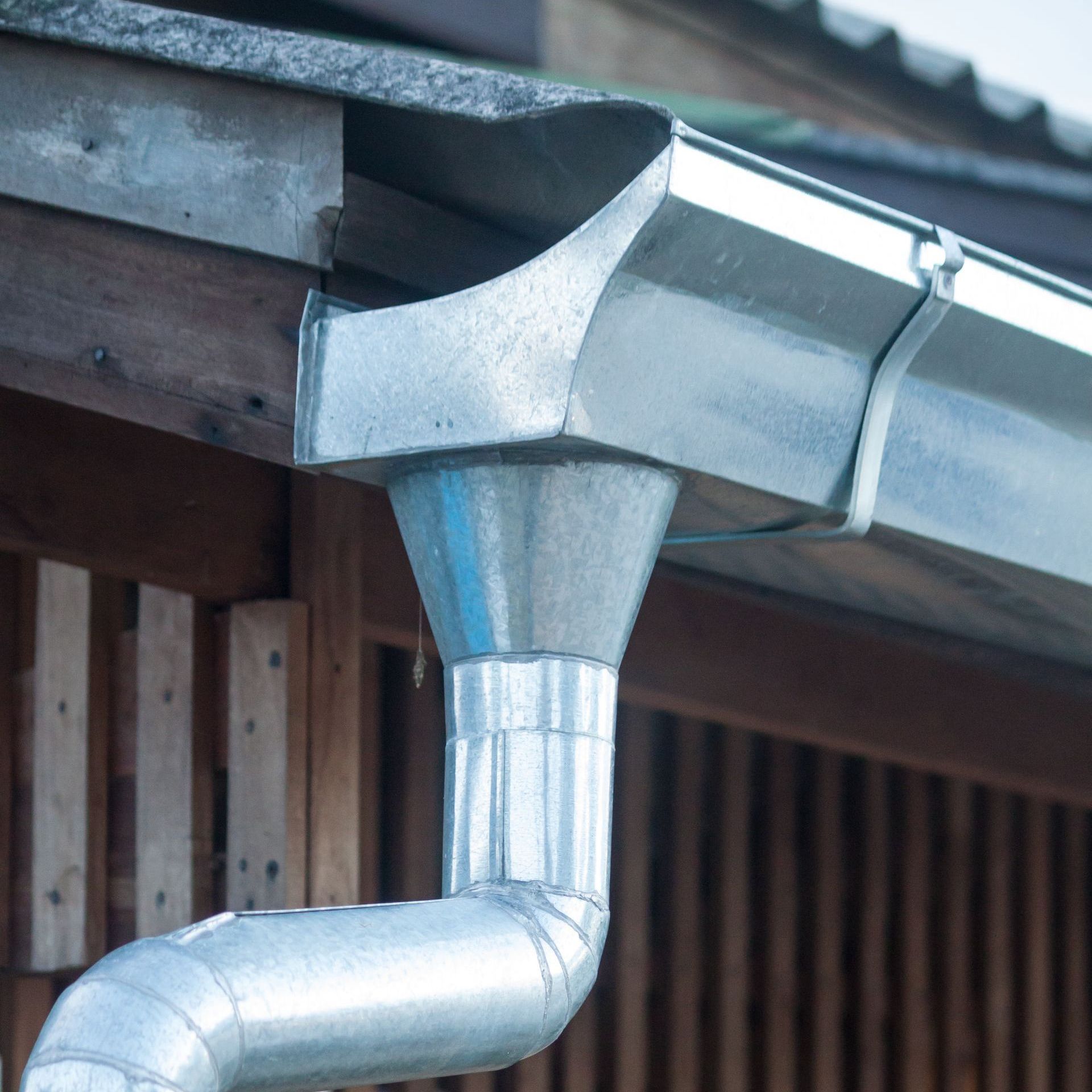 A close up of a metal rain gutter on the side of a building.