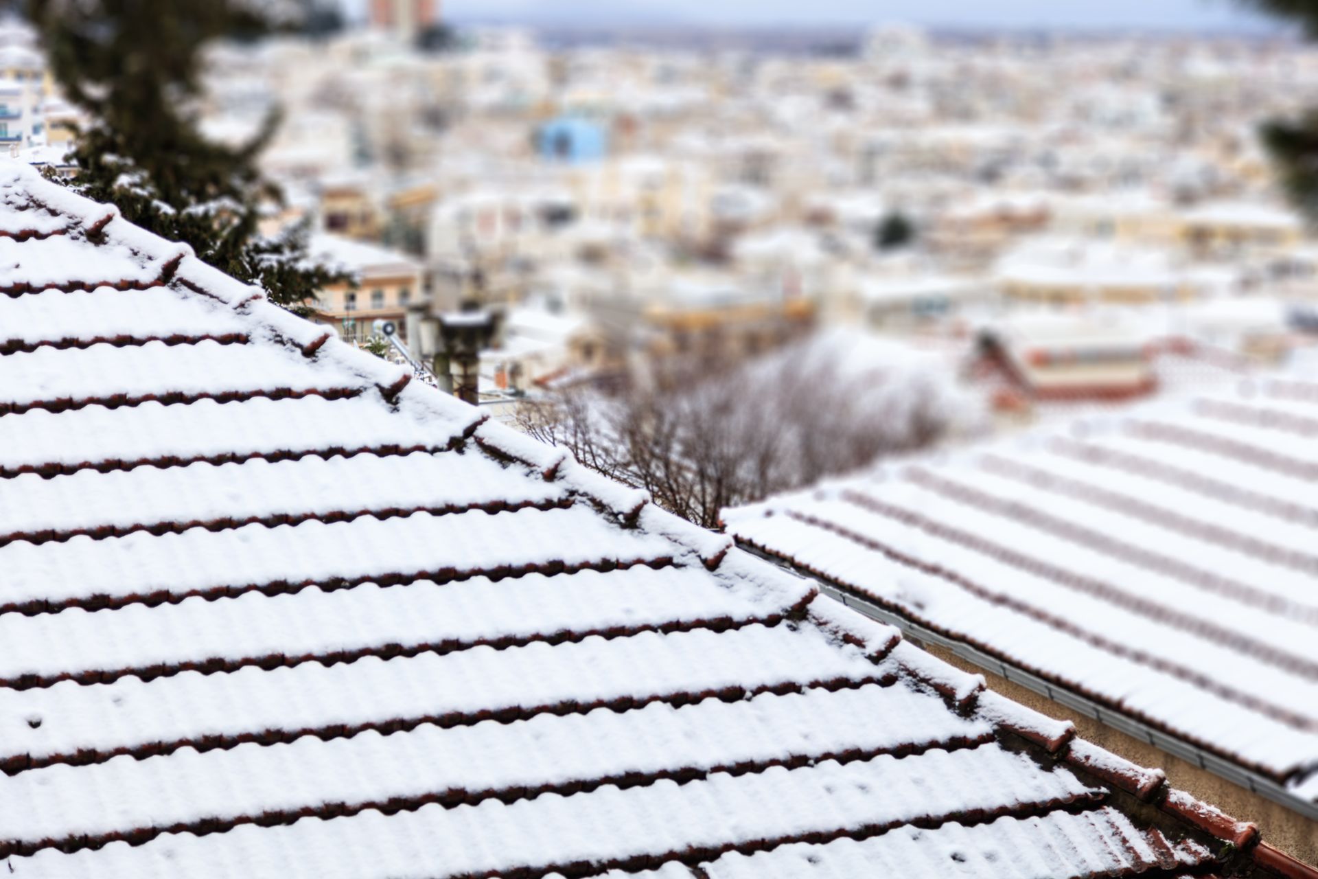 A roof covered in snow with a city in the background.