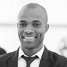 A man in a suit and tie is smiling in a black and white photo.