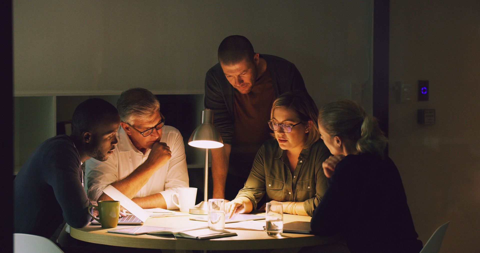 A group of people are sitting around a table in a dark room.