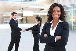 A woman is standing in front of a group of business people shaking hands.