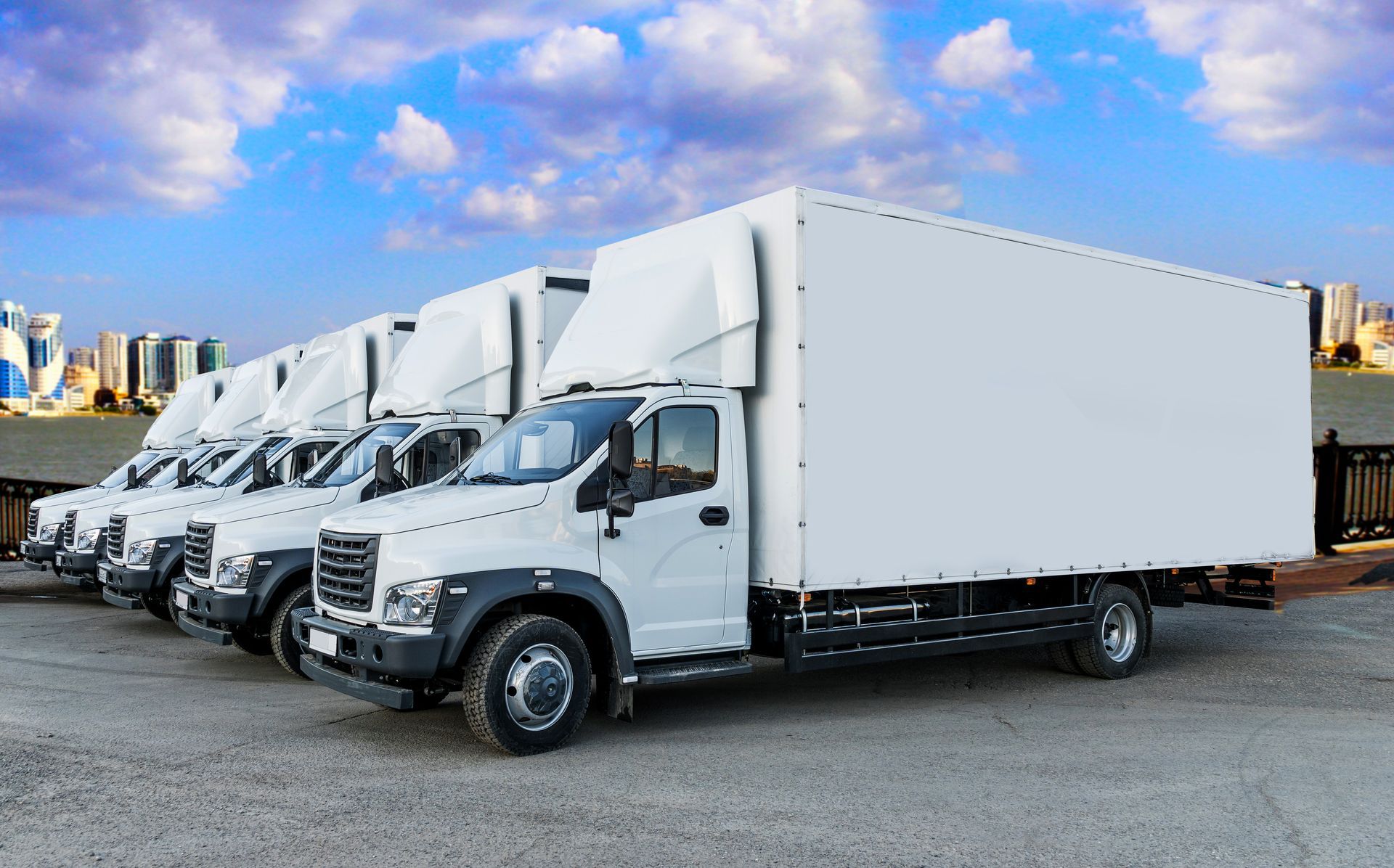 A row of white trucks are parked in a parking lot.