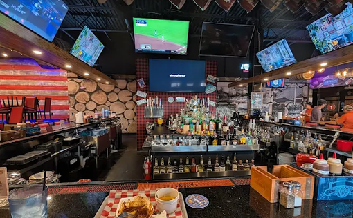 Interior of a bar, showing a bar with many liquor bottles, TVs, and a meal on the bar.