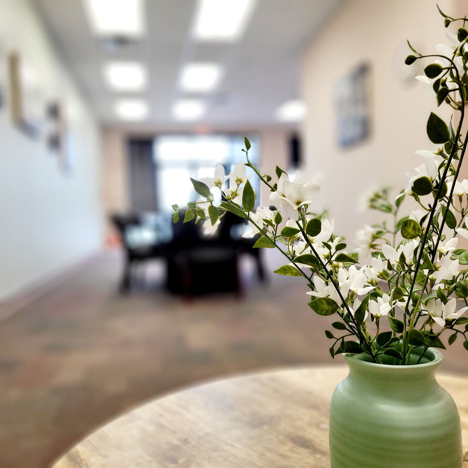 a green vase filled with white flowers sits on a table