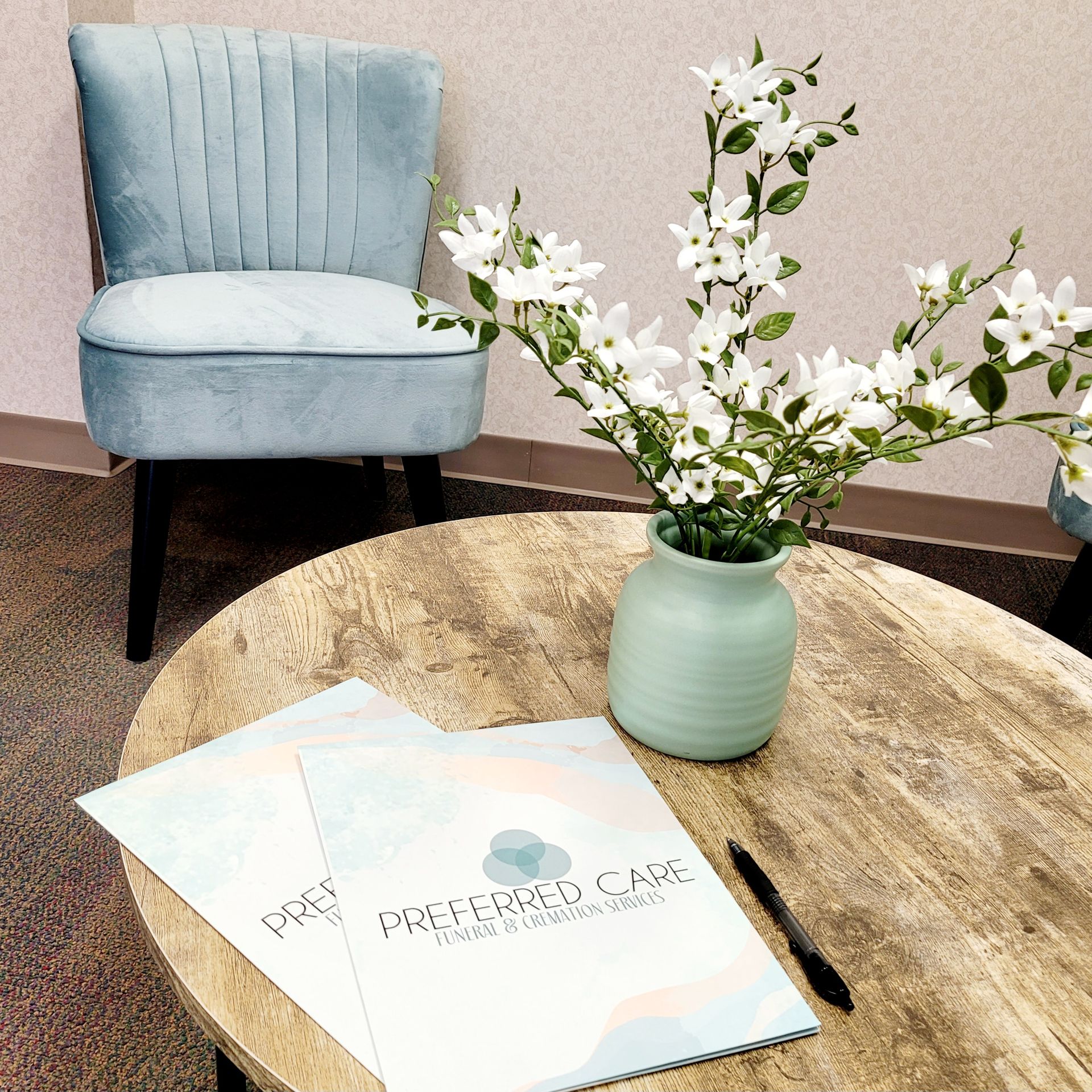 a vase of flowers sits on a table next to a chair