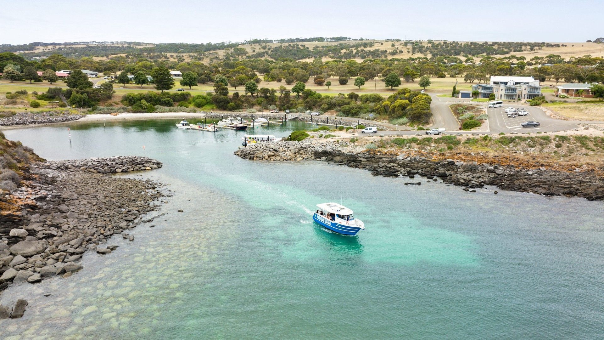 Boat entering harbor with turquoise water, and rocky shoreline