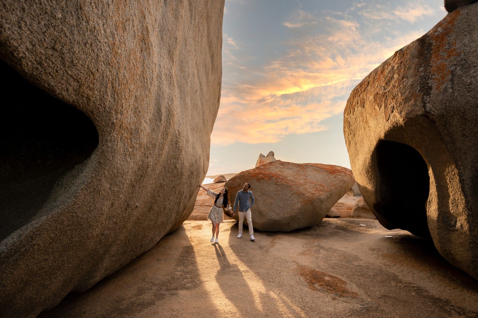 Couple walking between large rock formations at sunset