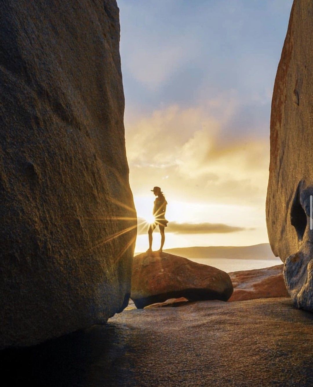 A couple are sitting on a rock overlooking the ocean