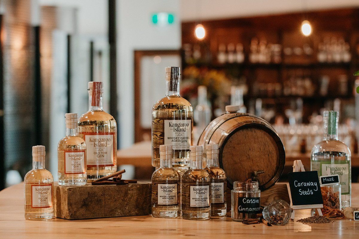 Bottles of spirits and small jars of ingredients on a bar, with a wooden barrel.