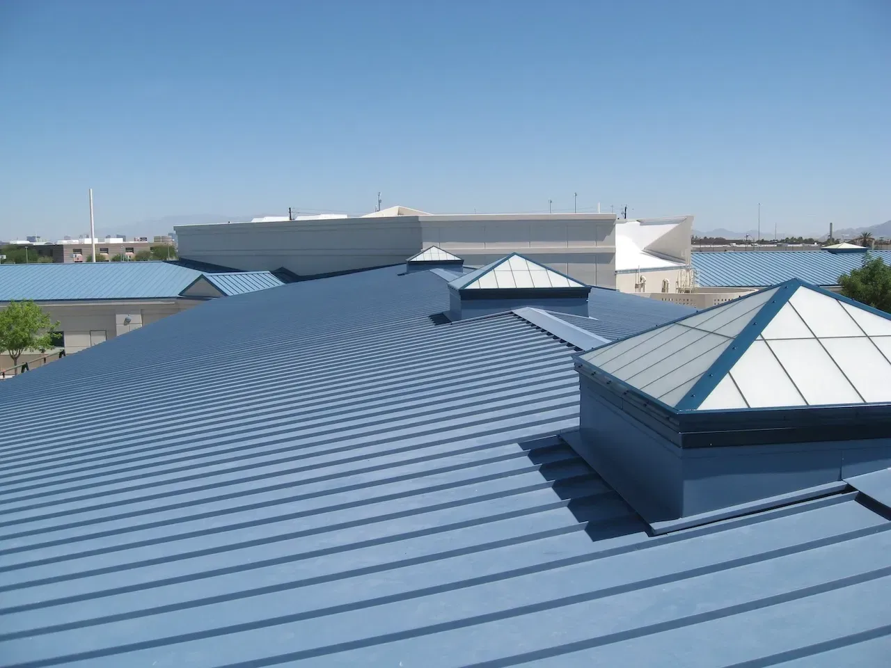 Blue metal roof with several skylights, under a clear blue sky.
