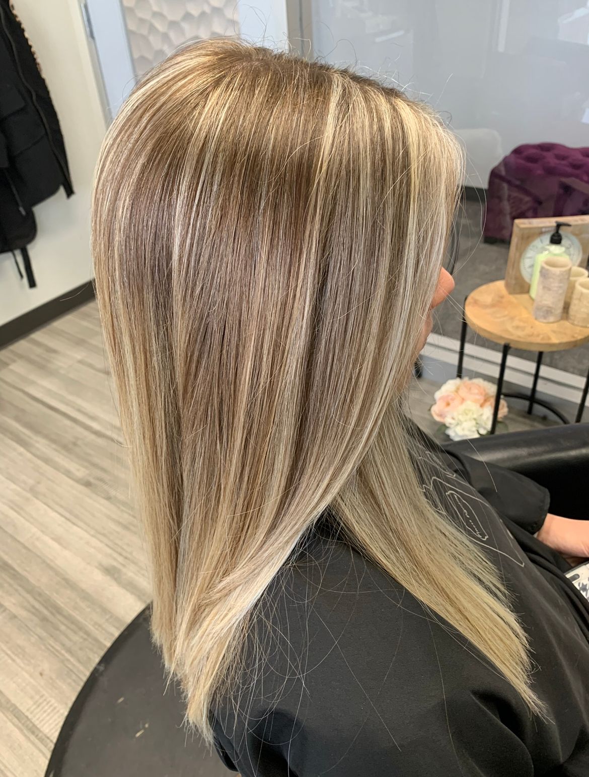 A woman with long blonde hair is sitting in a chair in a salon.