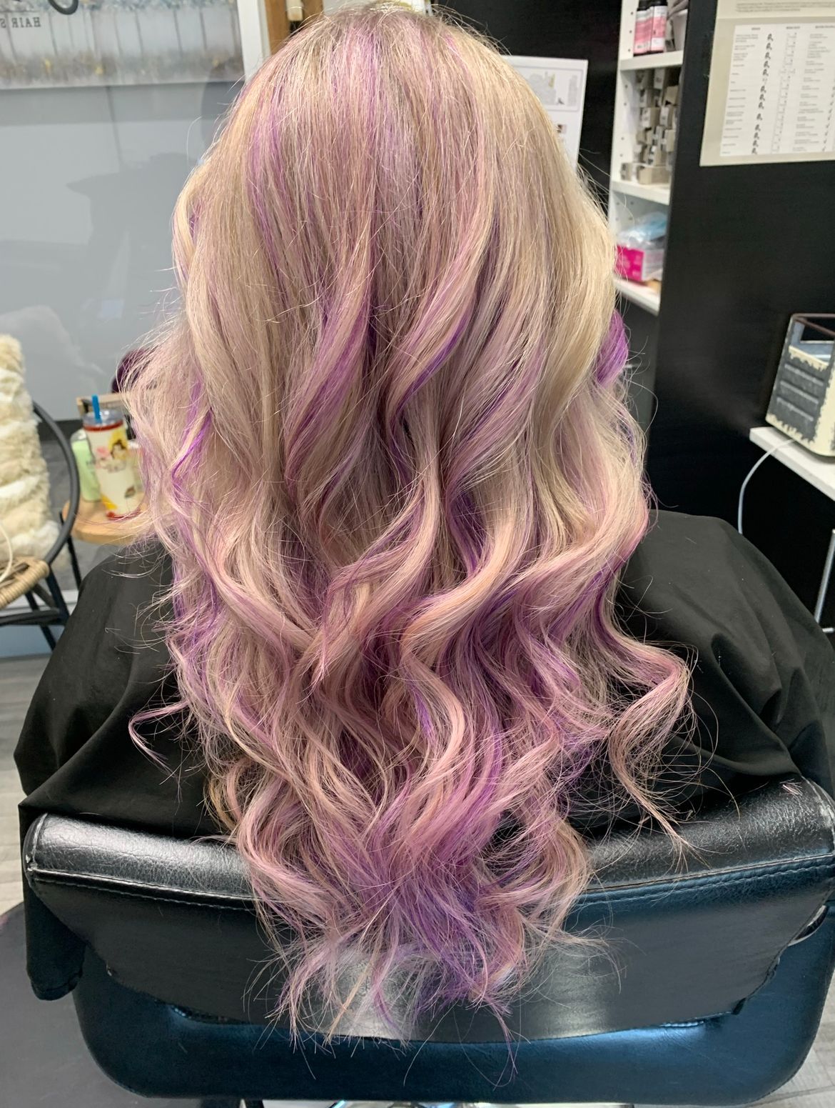 A woman with blonde and purple hair is sitting in a chair.