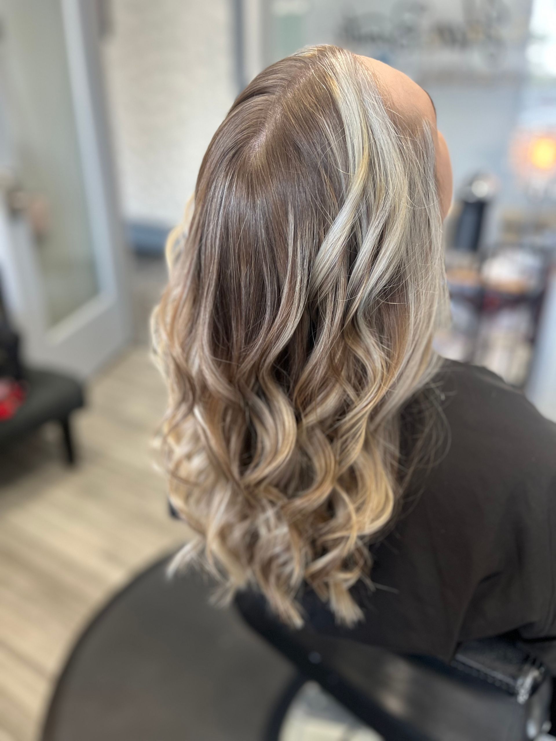 A woman is sitting in a chair with her hair in a salon.