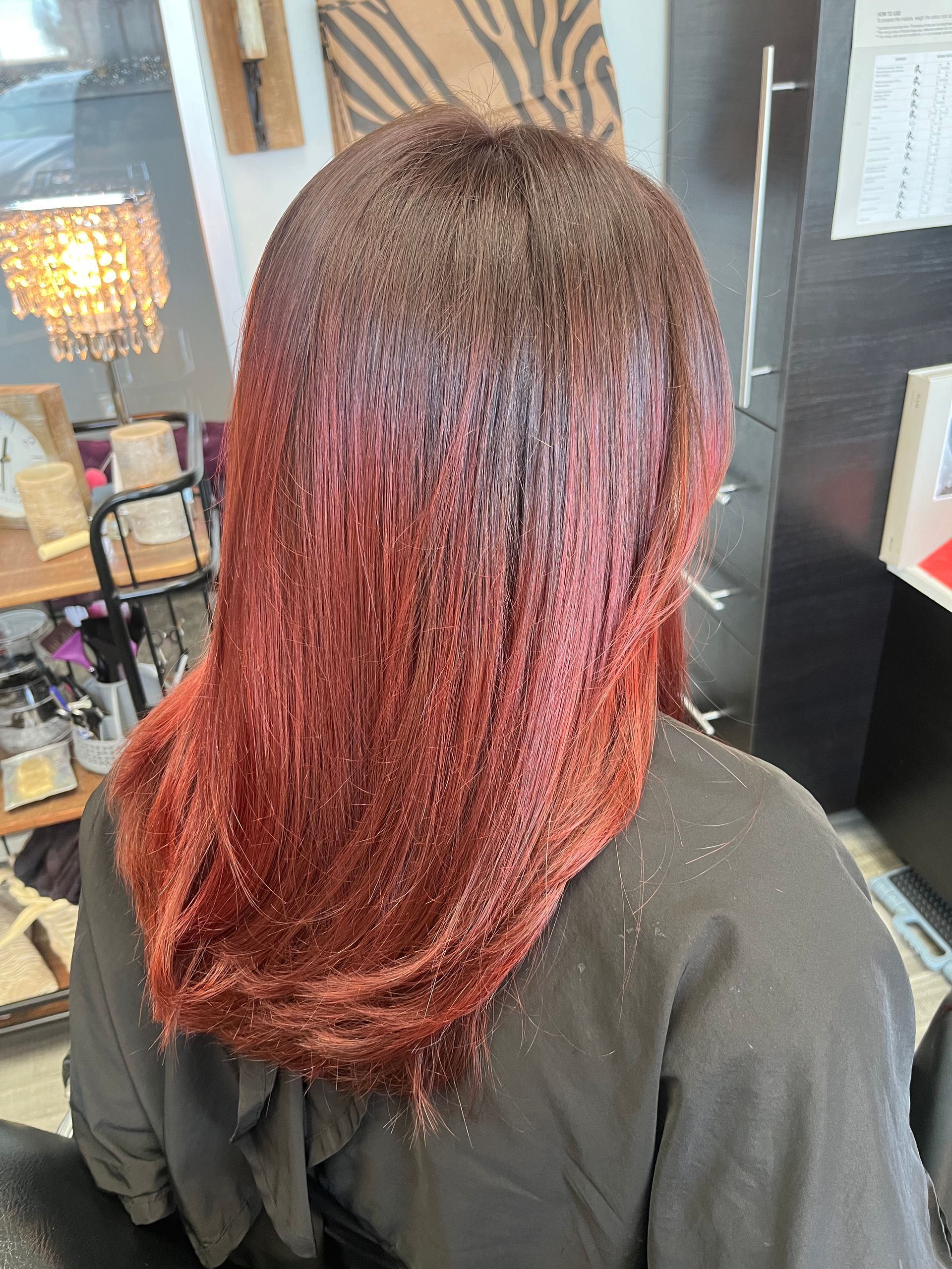 A woman with red hair is sitting on a chair in a salon.