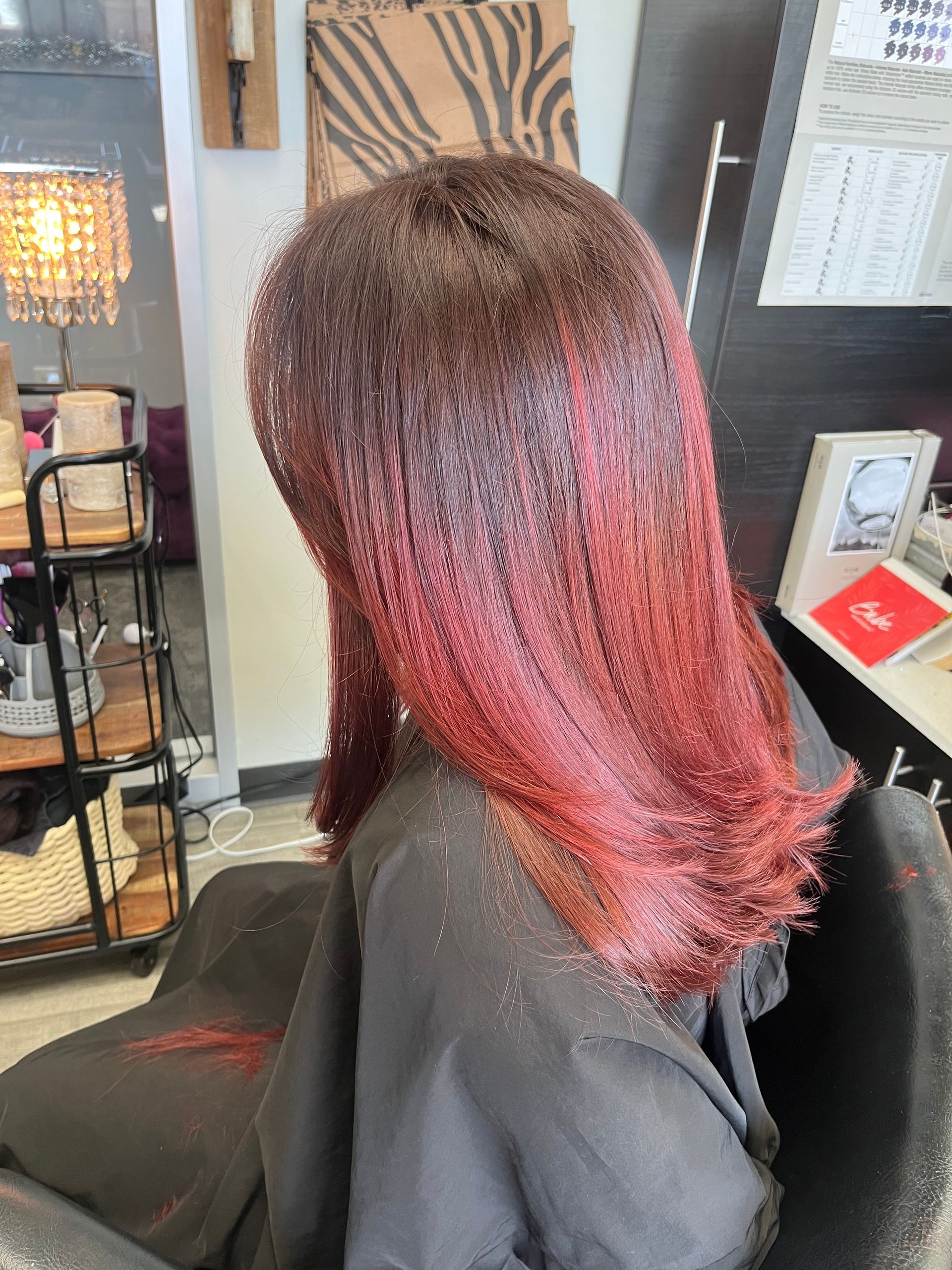 A woman with red hair is sitting in a chair in a salon.