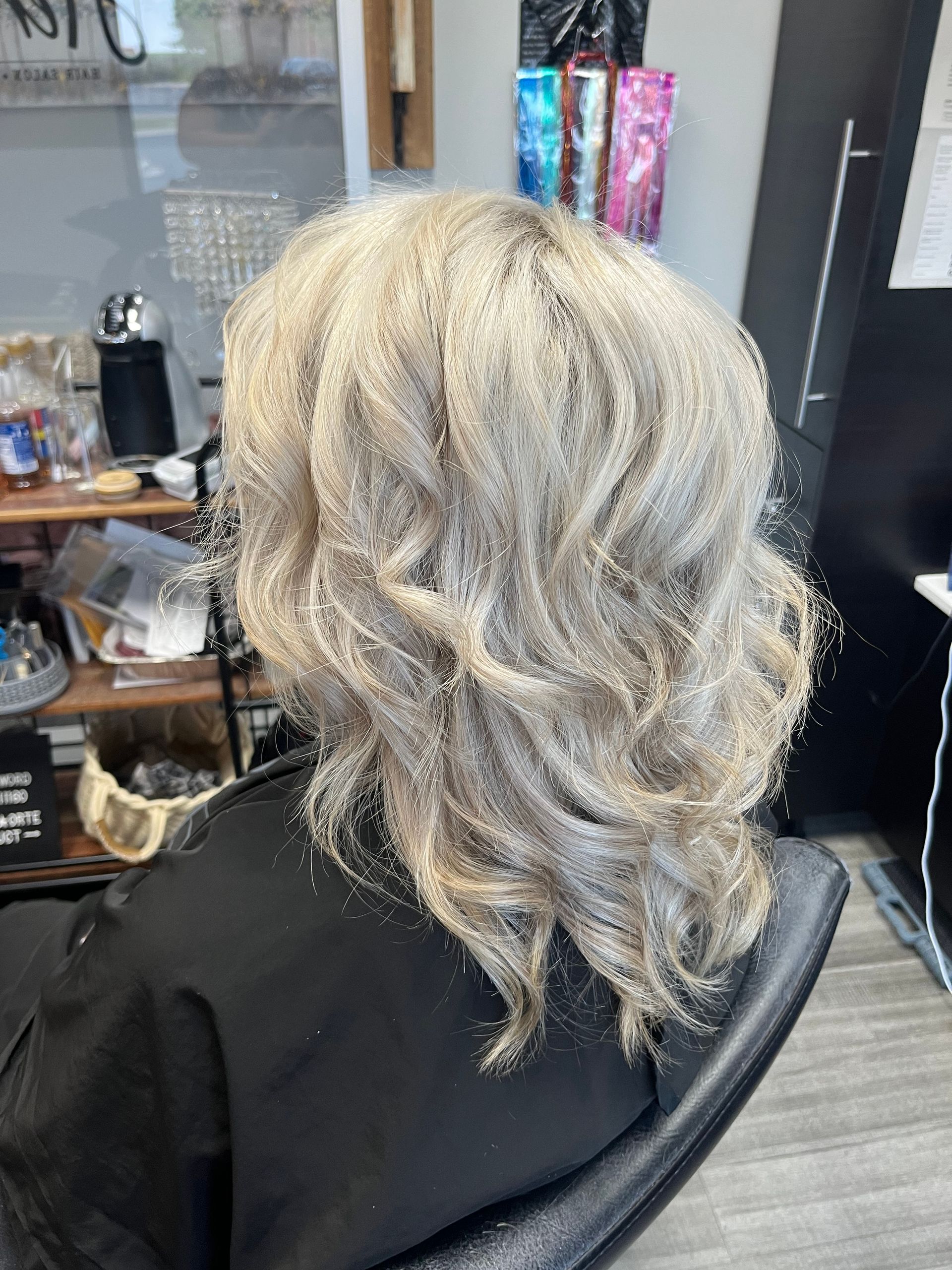 A woman with blonde hair is sitting in a chair in a salon.