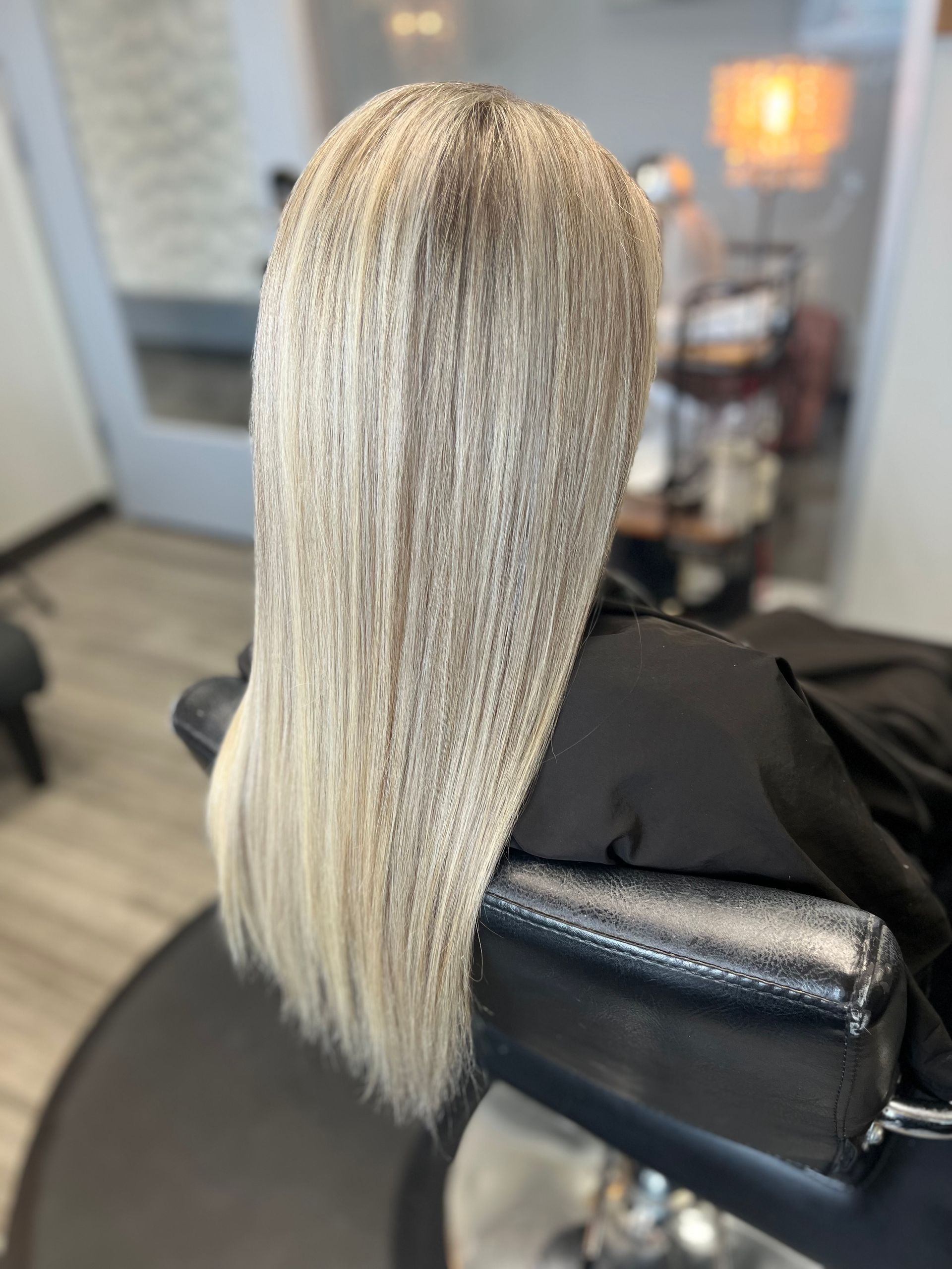 A woman with blonde hair is sitting in a chair in a salon.
