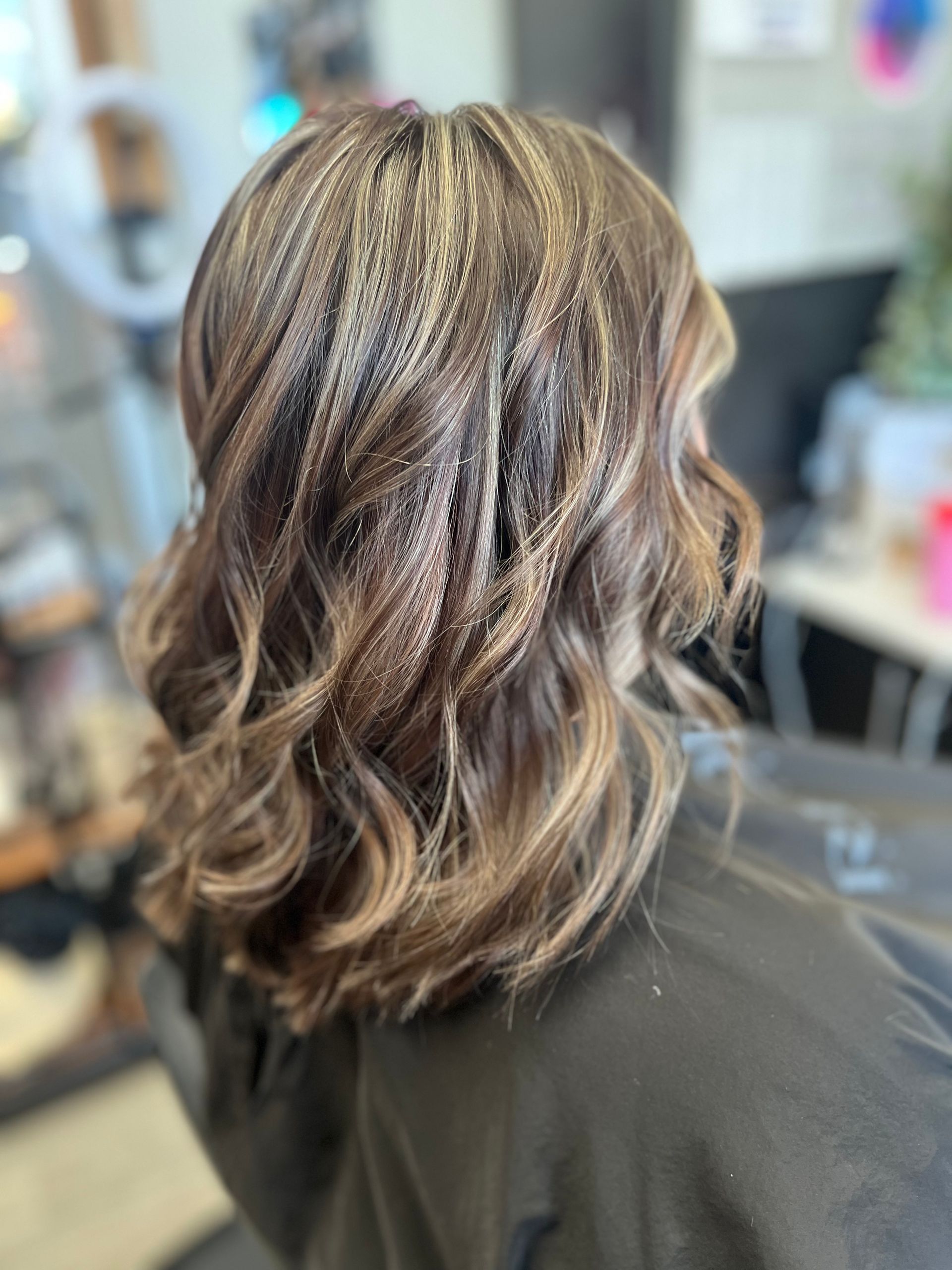 A woman with long hair is sitting in a chair in a salon.