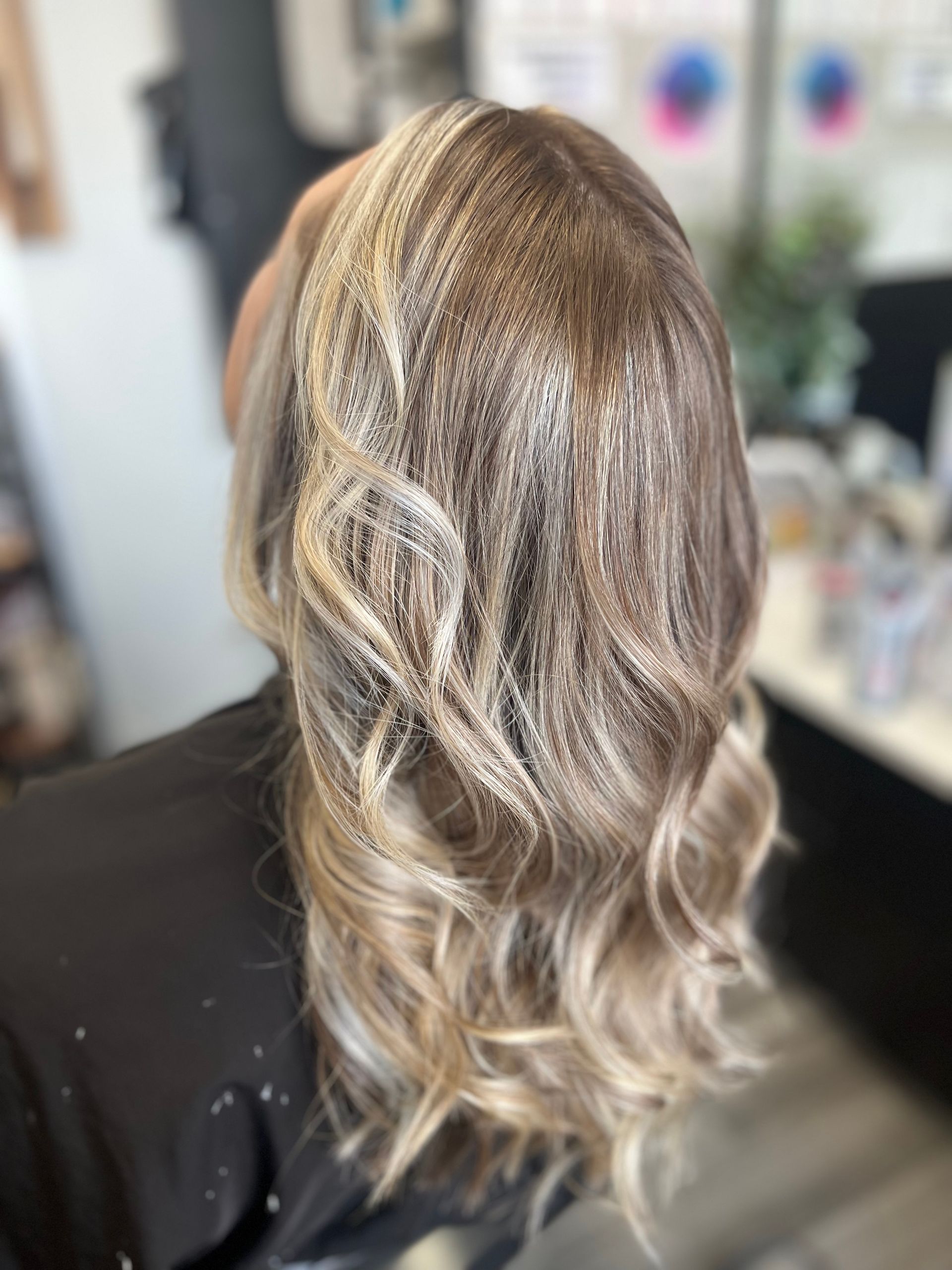 A woman with blonde hair is sitting in a chair in a salon.