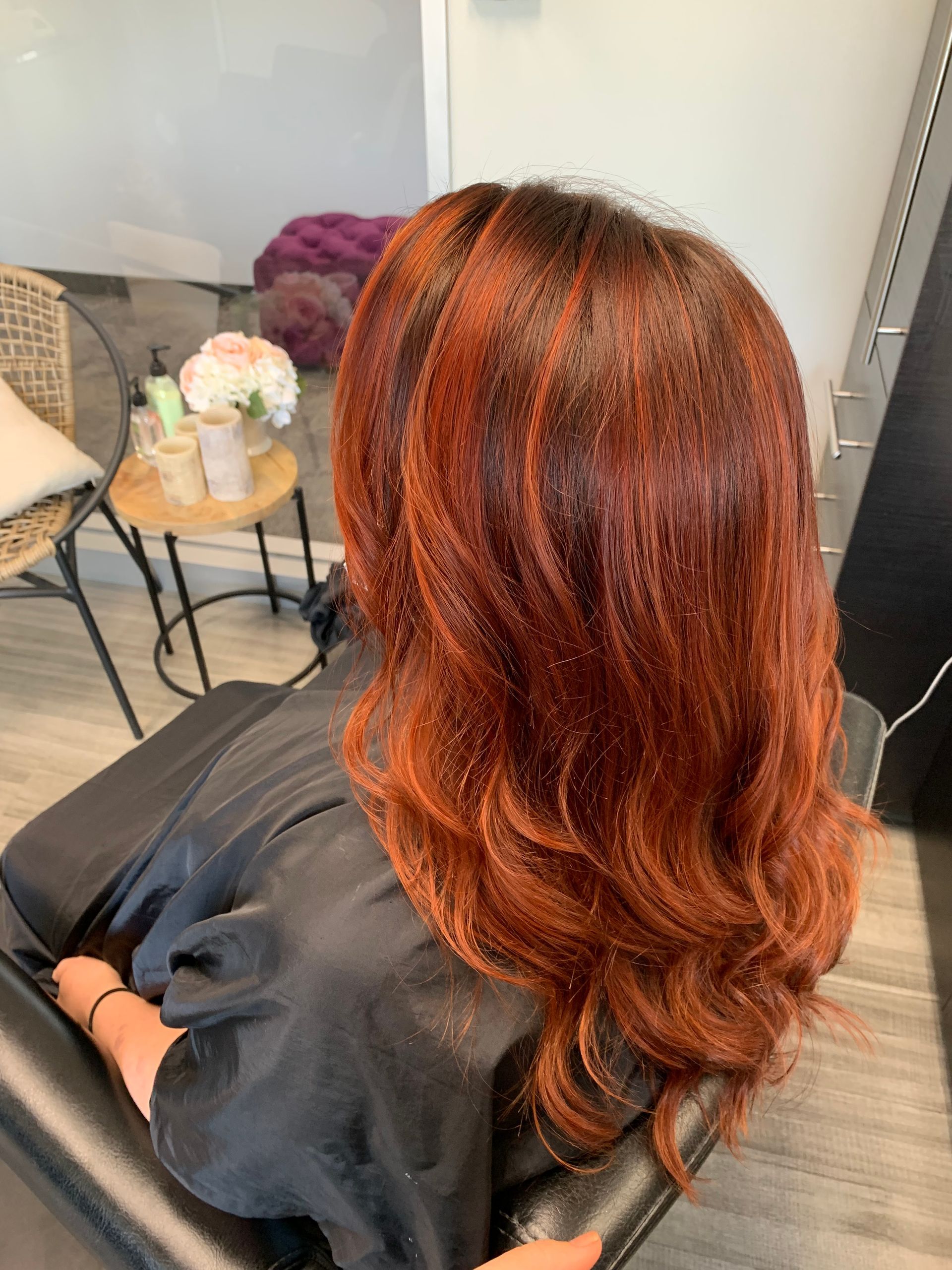A woman with red hair is sitting in a chair in a salon.
