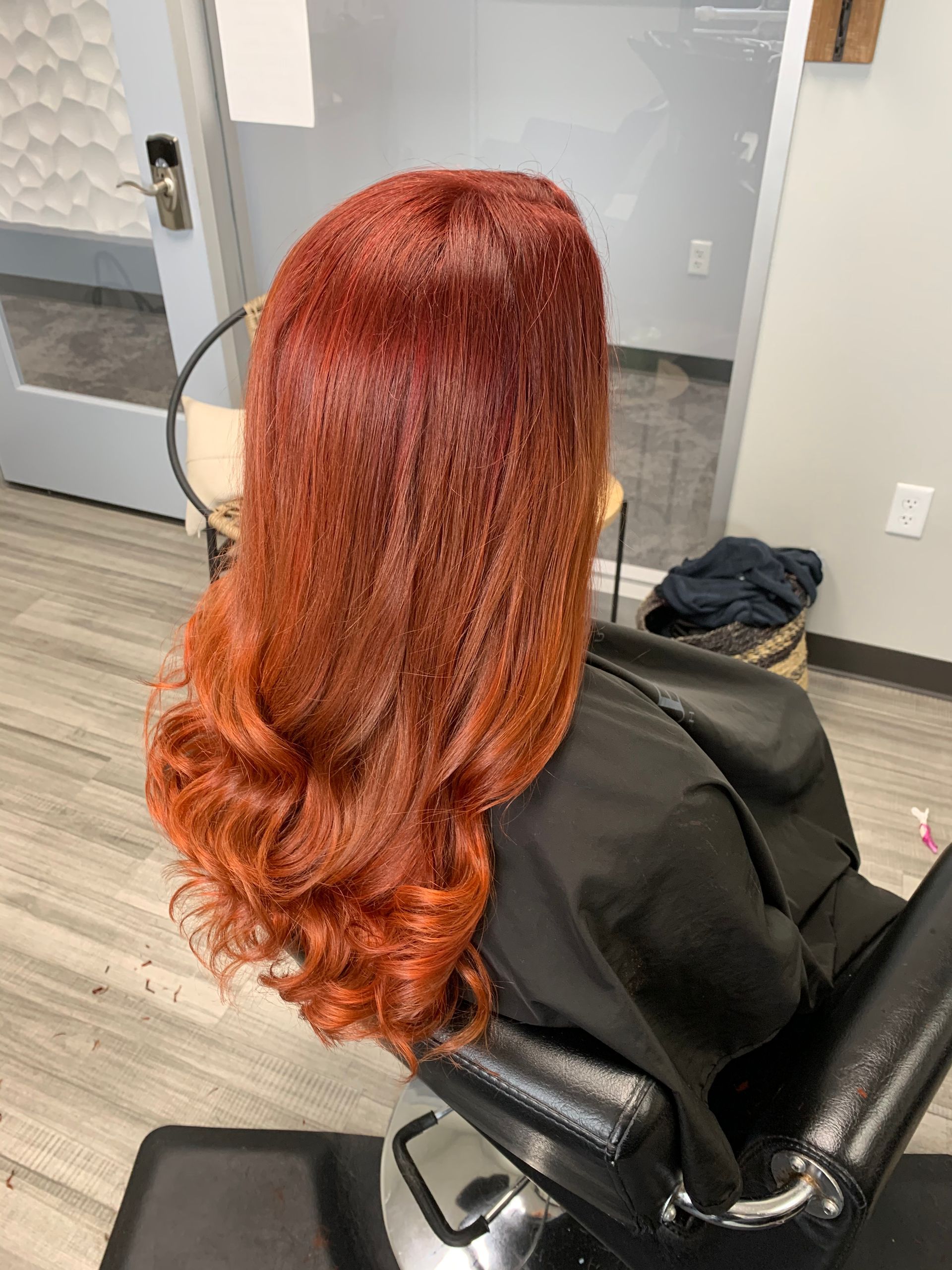 A woman with red hair is sitting in a chair in a salon.