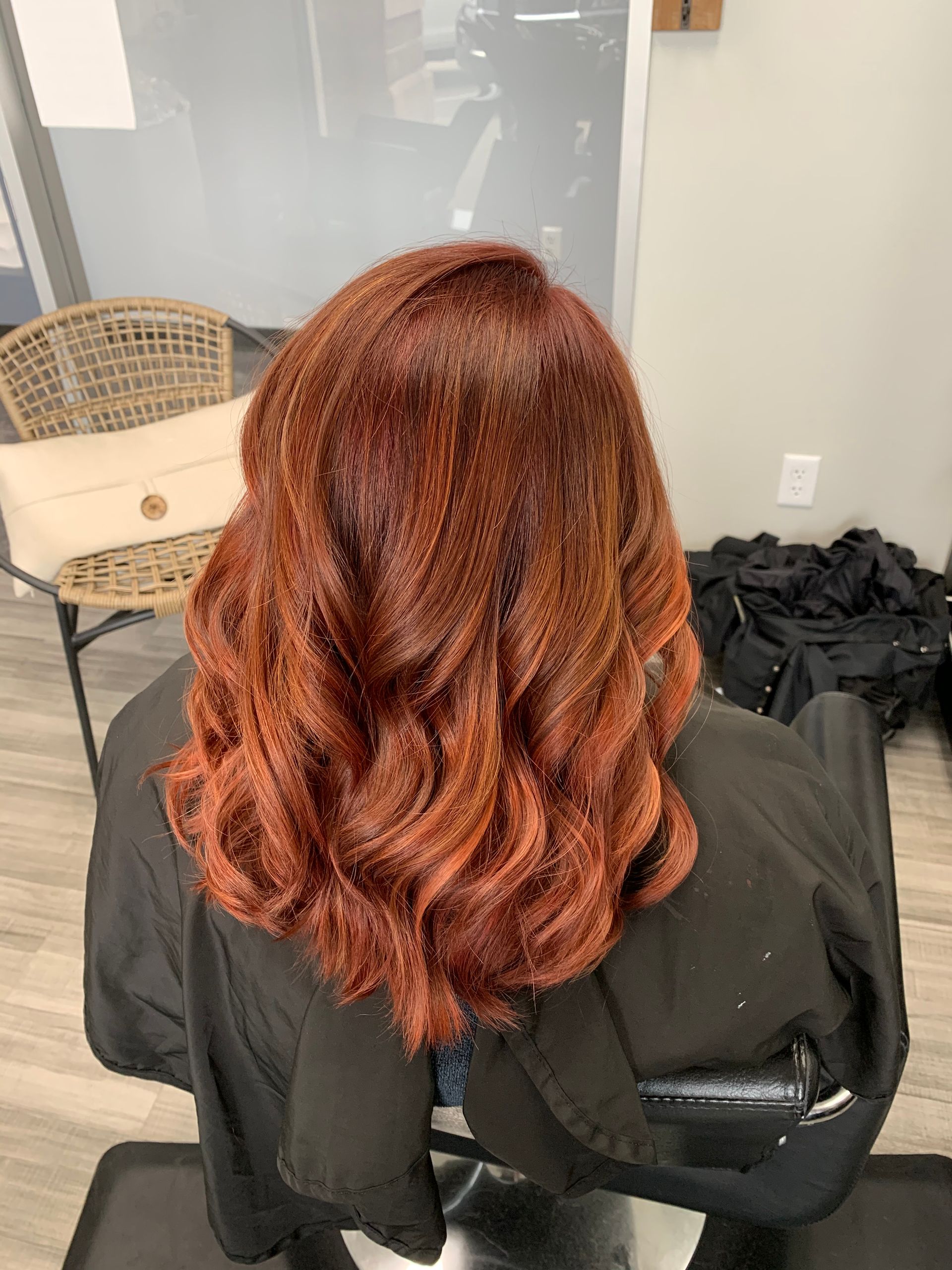 A woman with red hair is sitting in a chair in a salon.