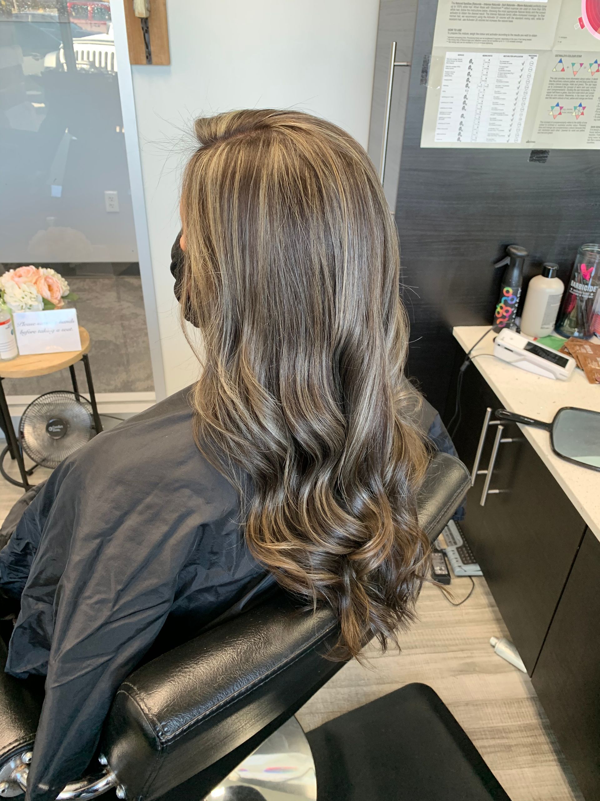 A woman is sitting in a chair with her hair dyed in a salon.