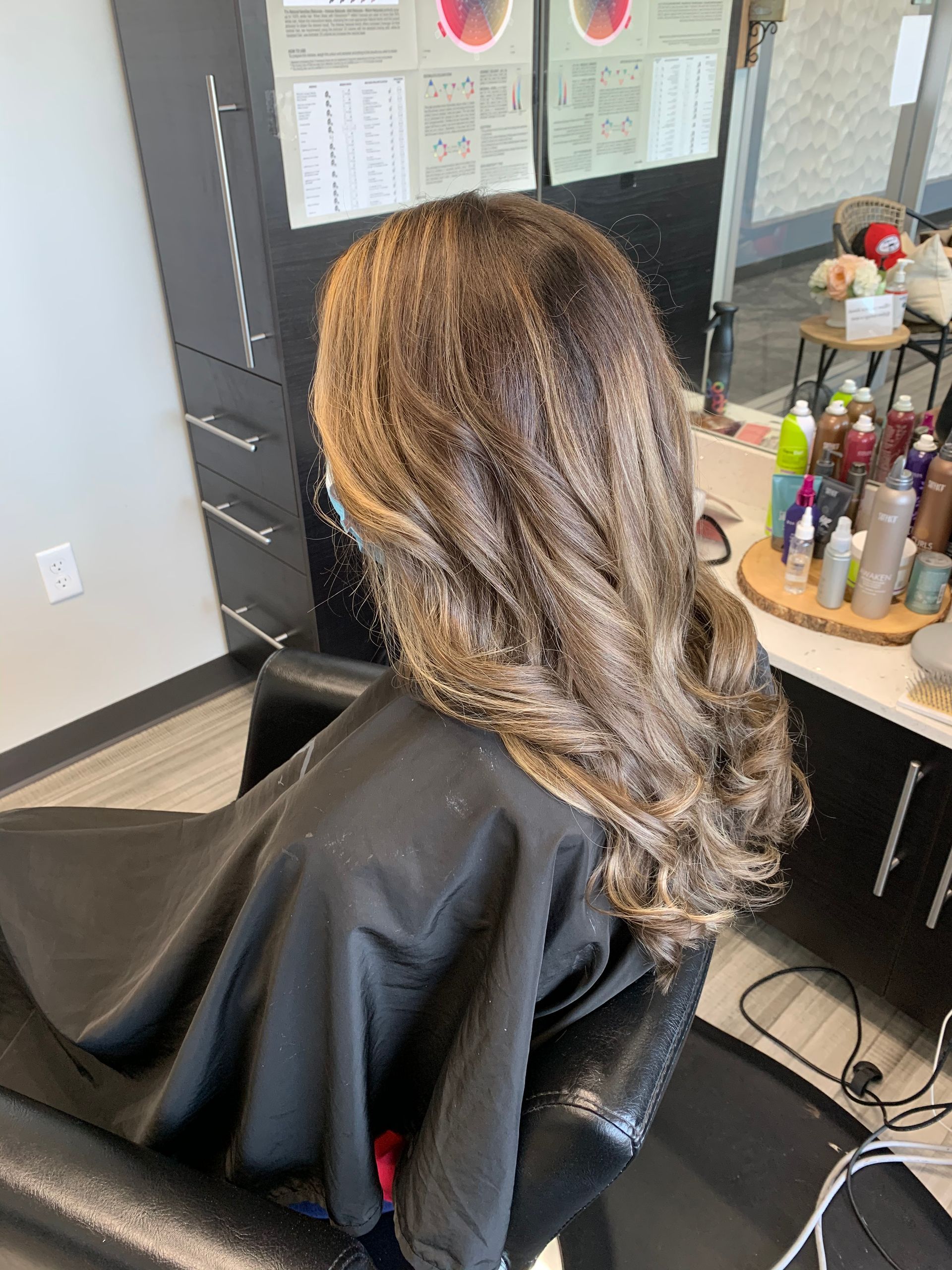 A woman is sitting in a chair in a salon getting her hair done.