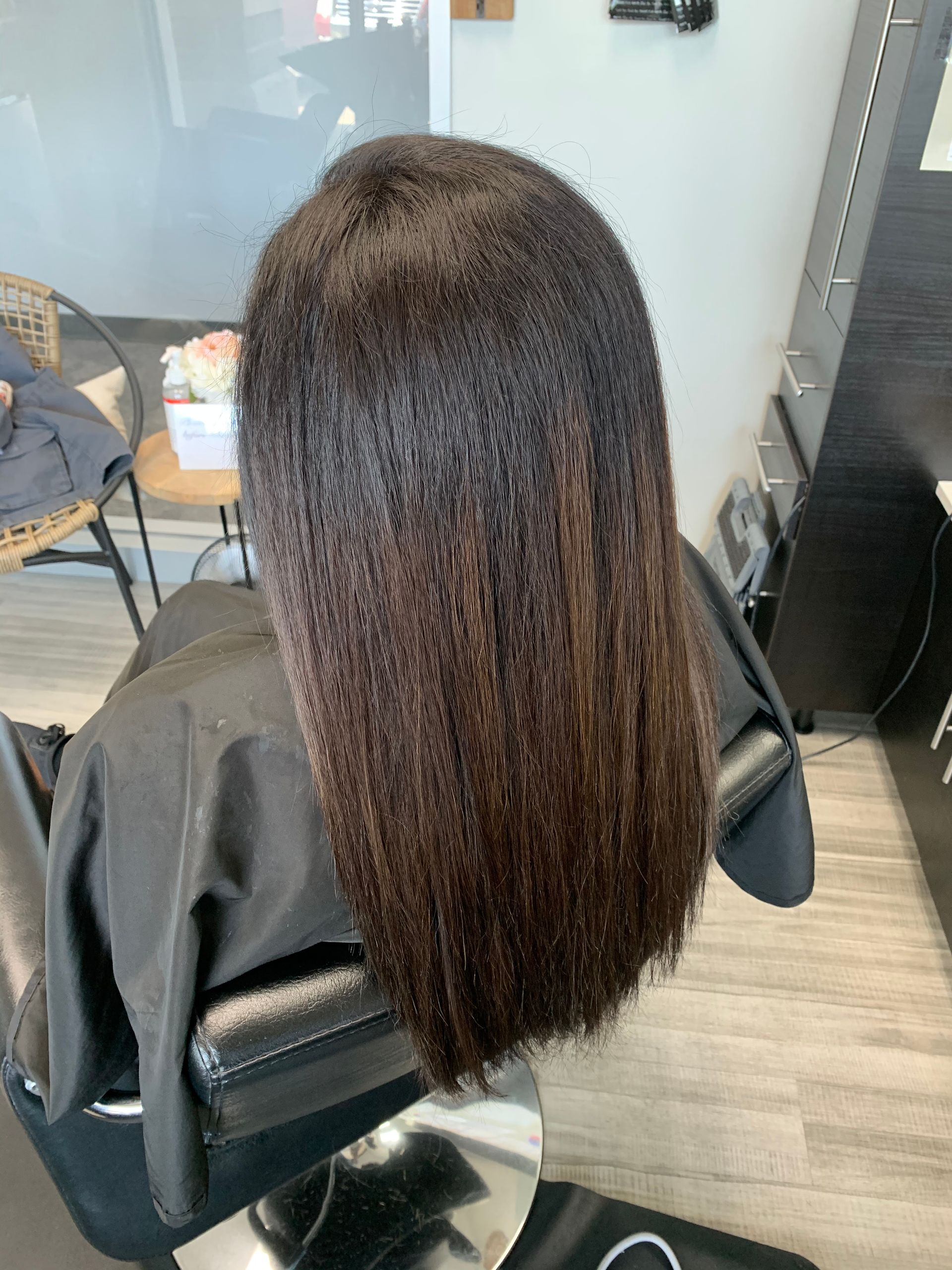 A woman is sitting in a chair with her hair in a salon.
