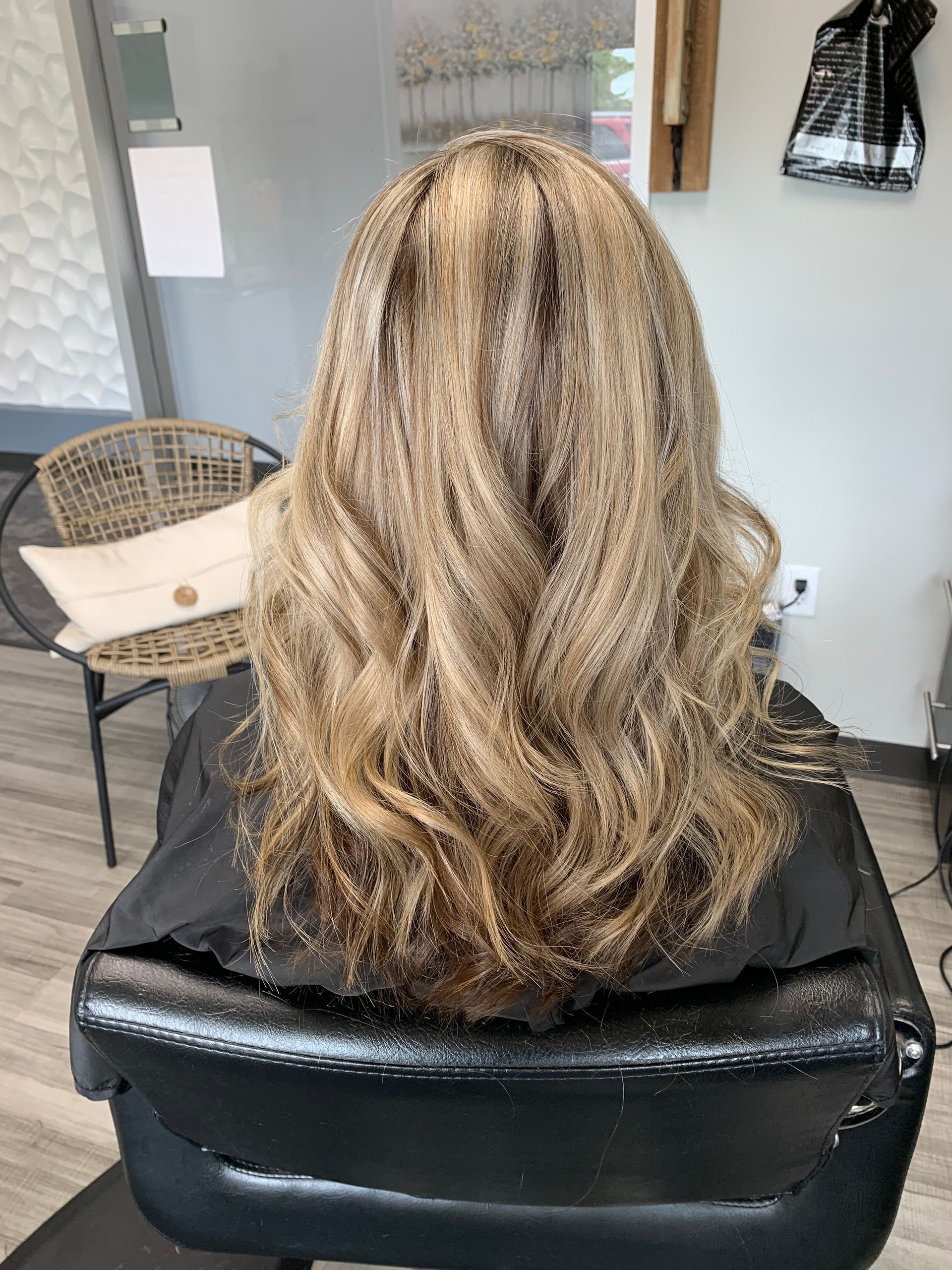 A woman with long blonde hair is sitting in a chair in a salon.
