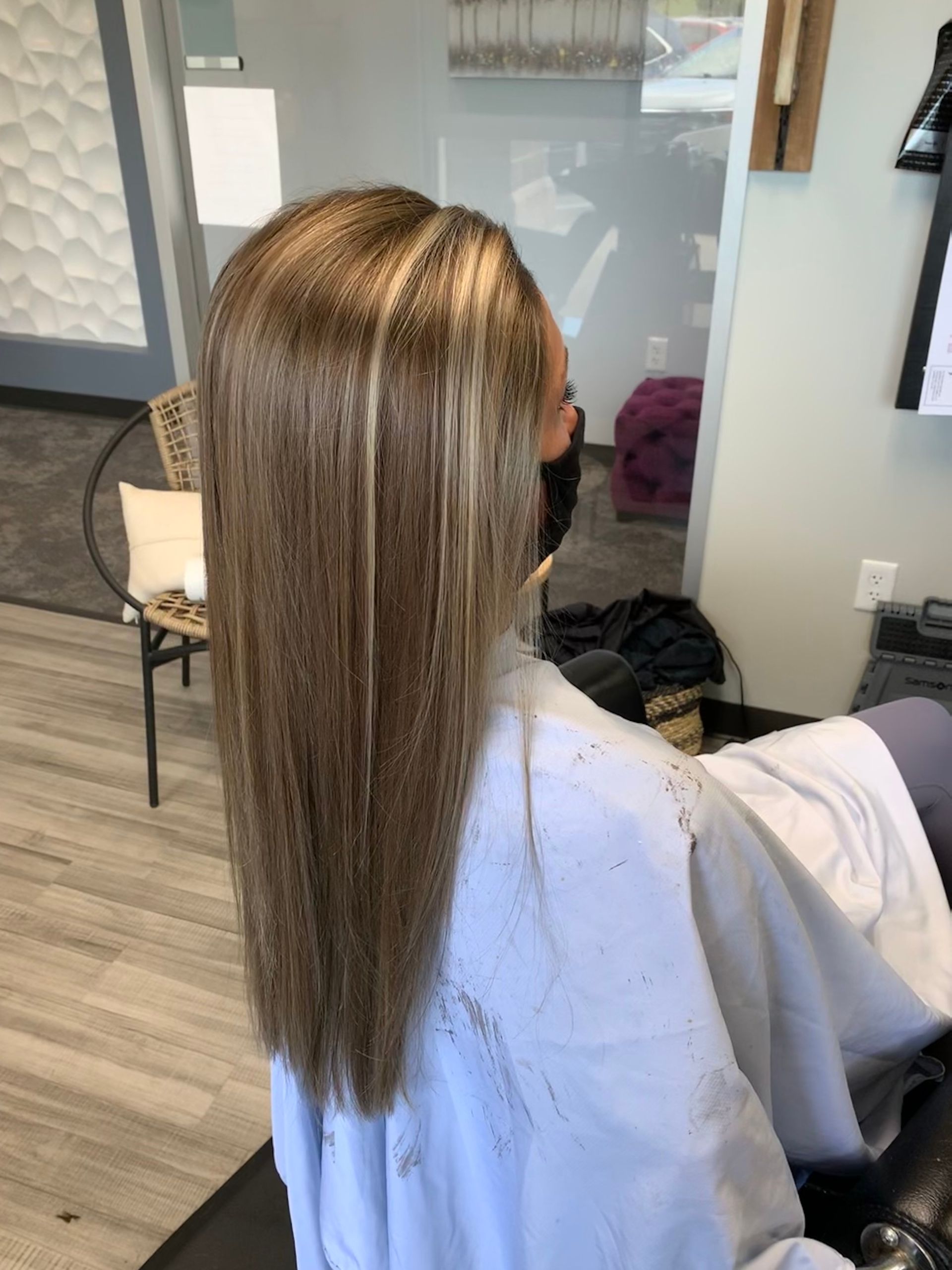 A woman is getting her hair cut in a salon while wearing a mask.