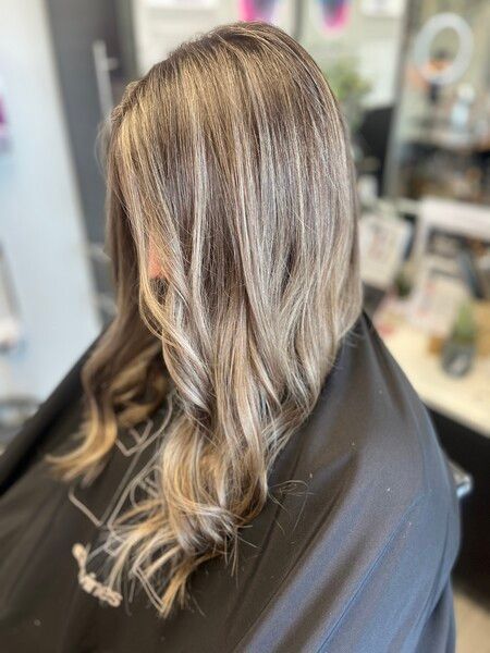 A woman with long blonde hair is sitting in a chair in a salon.