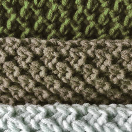 Close-up of three horizontal bands of knitted fabric in green, tan, and light blue with a textured, braided stitch.