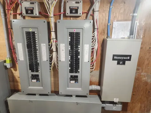A honeywell box is sitting next to three electrical panels.
