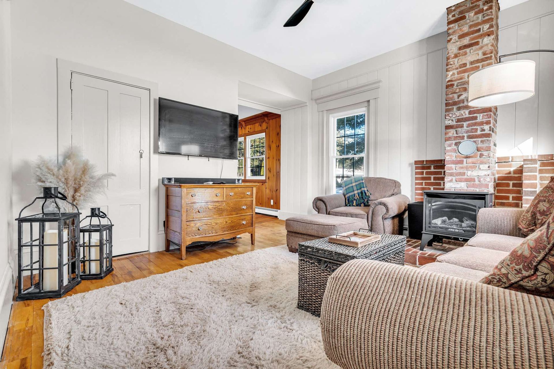 Cozy living room with a brick fireplace, TV, rug, sofa, and antique chest.