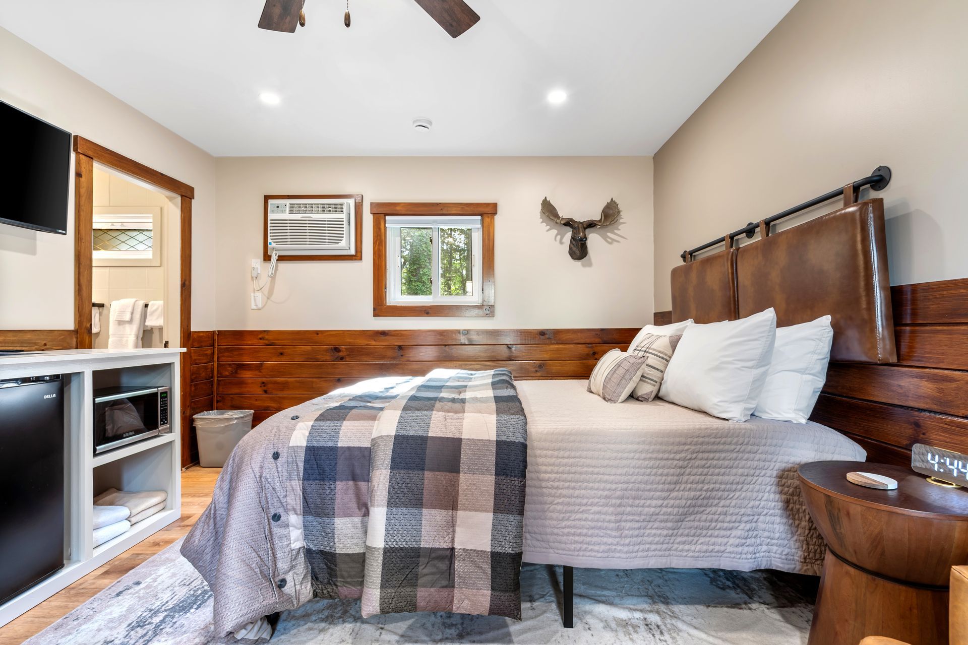 Cozy bedroom with a bed, wooden headboard, and a moose head wall decoration.