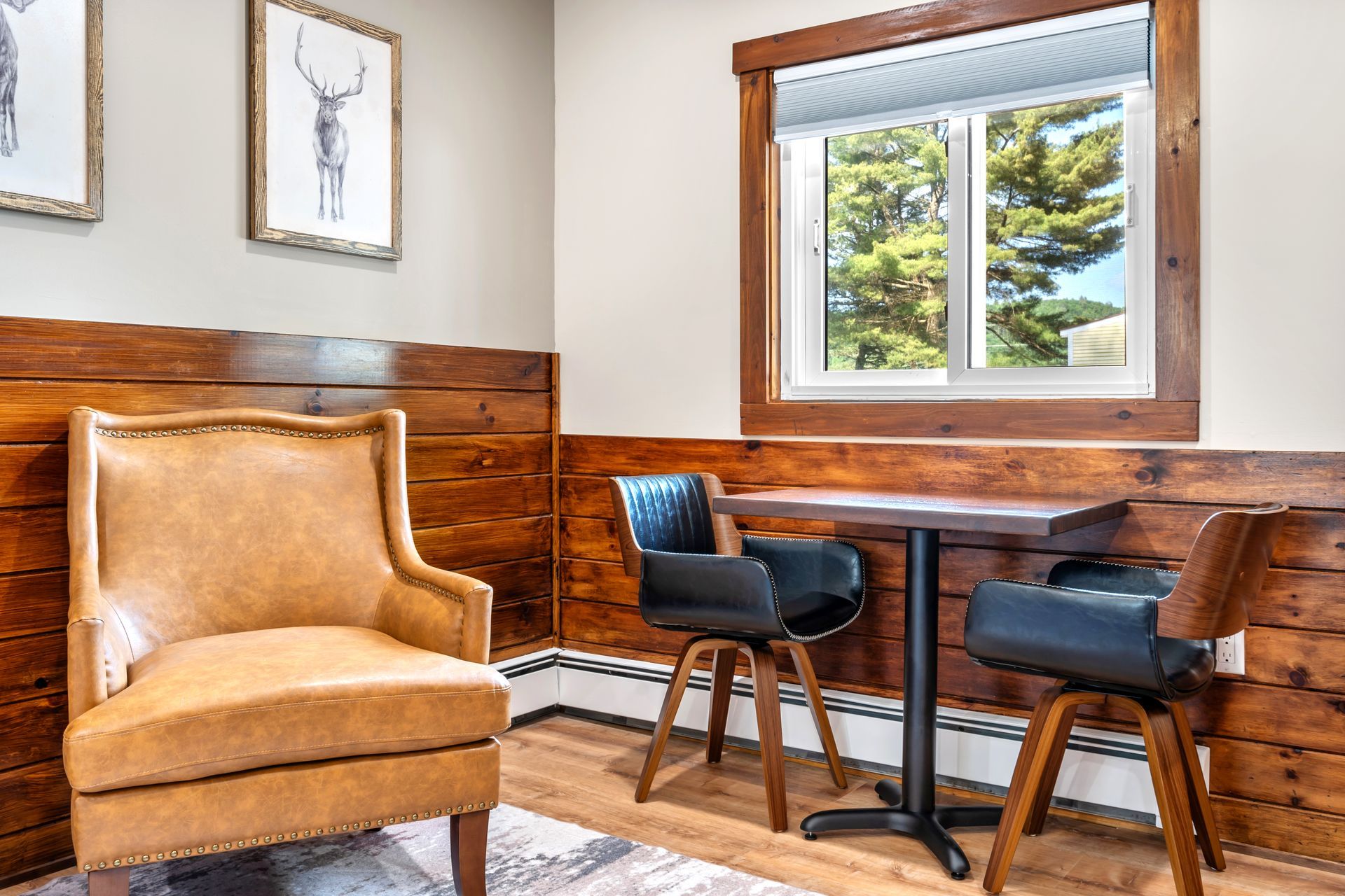 Cozy corner with a leather armchair, small table with two swivel chairs, wood paneling, and a window.