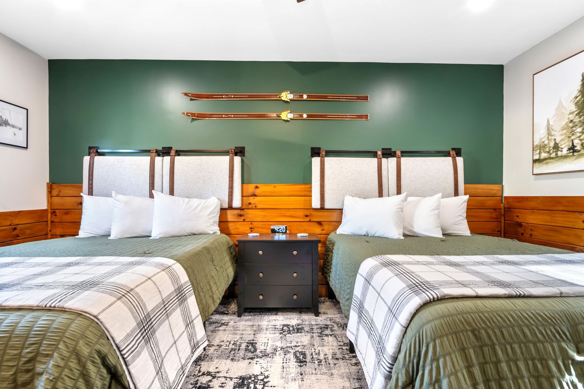 Two beds in a green and wood-paneled room with a ski decor above the beds.