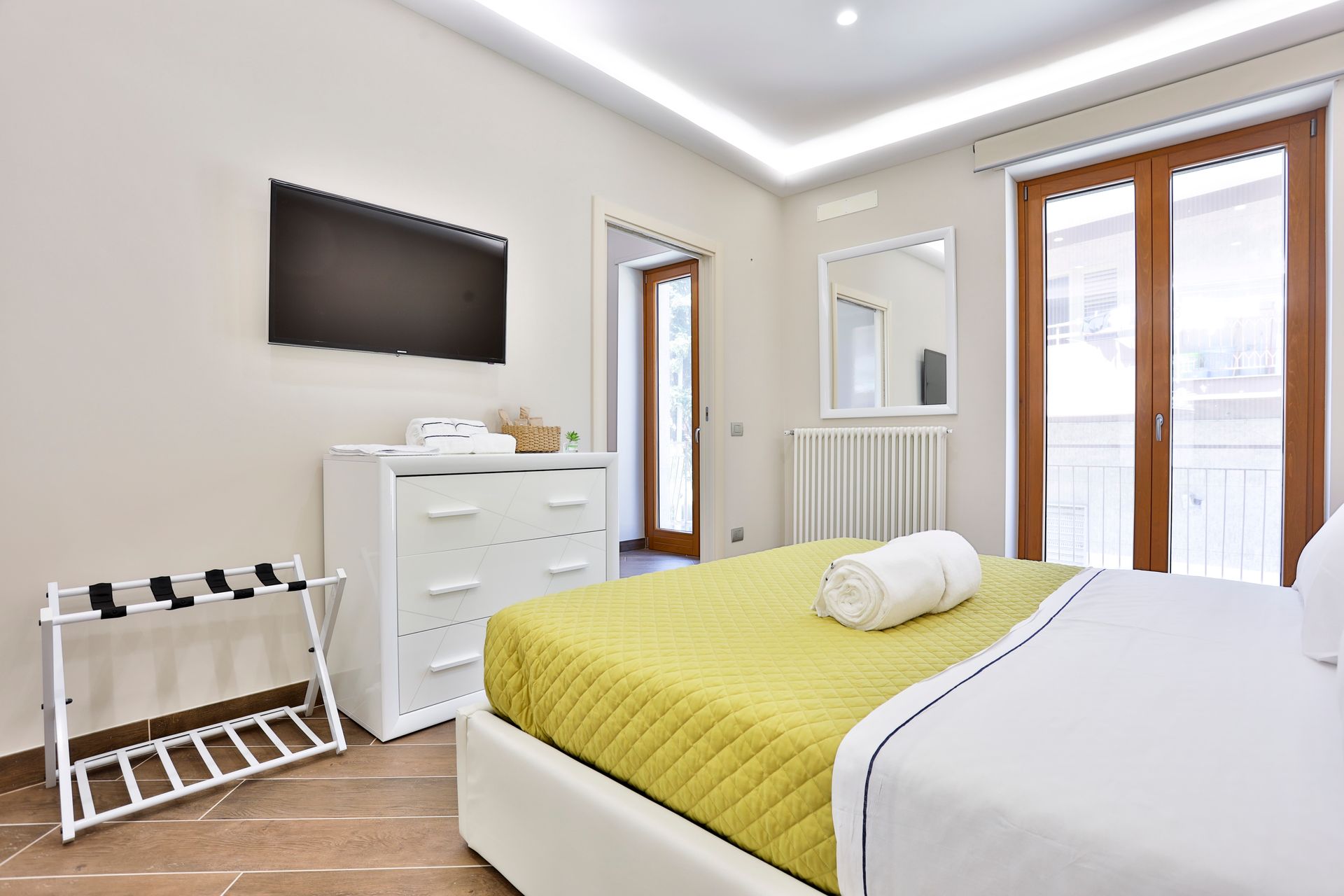 Hotel room with a bed, dresser, TV, and glass sliding doors.