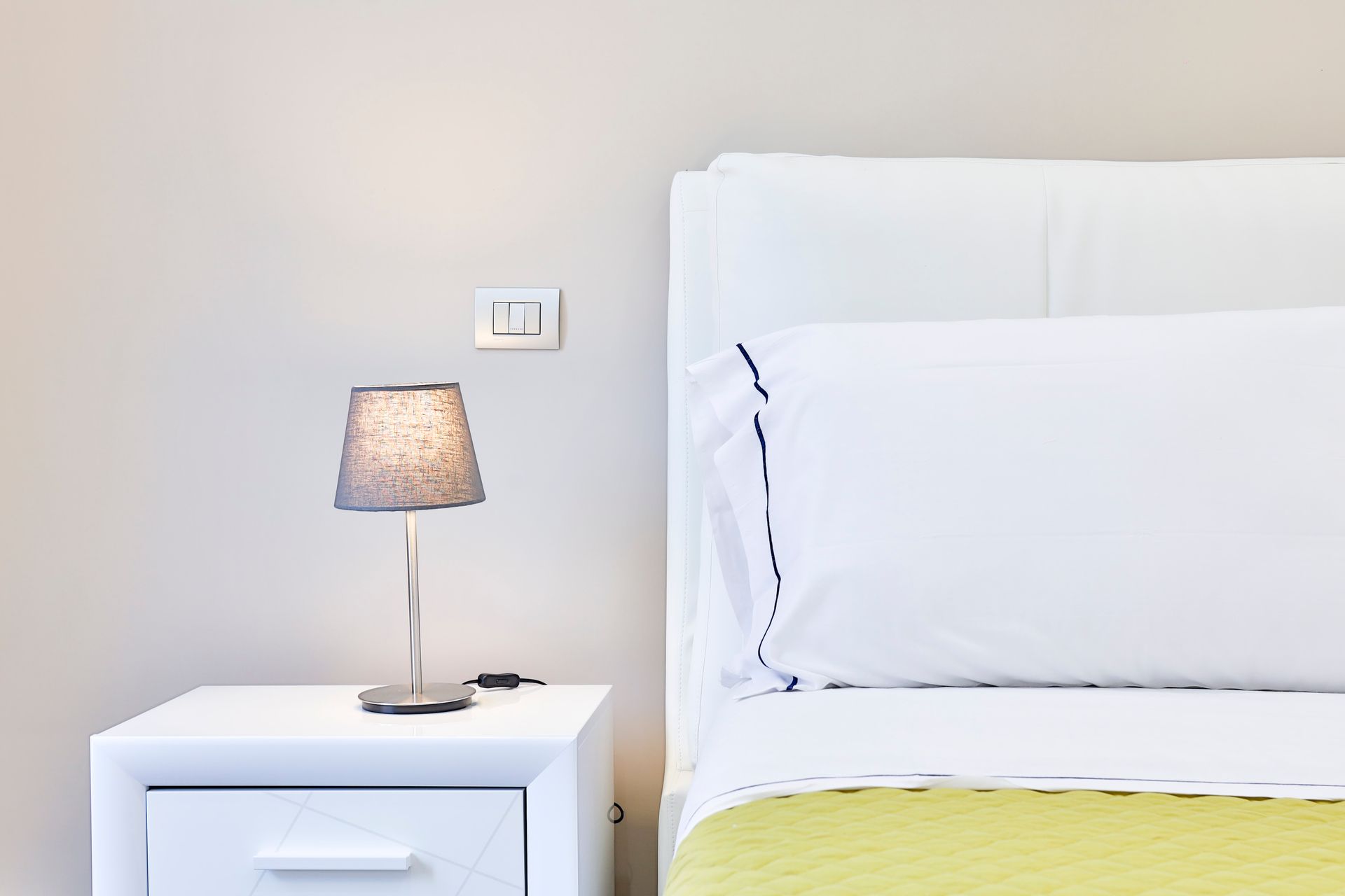 Bedroom with a bed and a bedside table with a lamp on it.