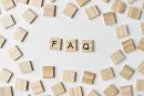 Wooden tiles spelling “FAQ” surrounded by scattered beige letter blocks on a white background