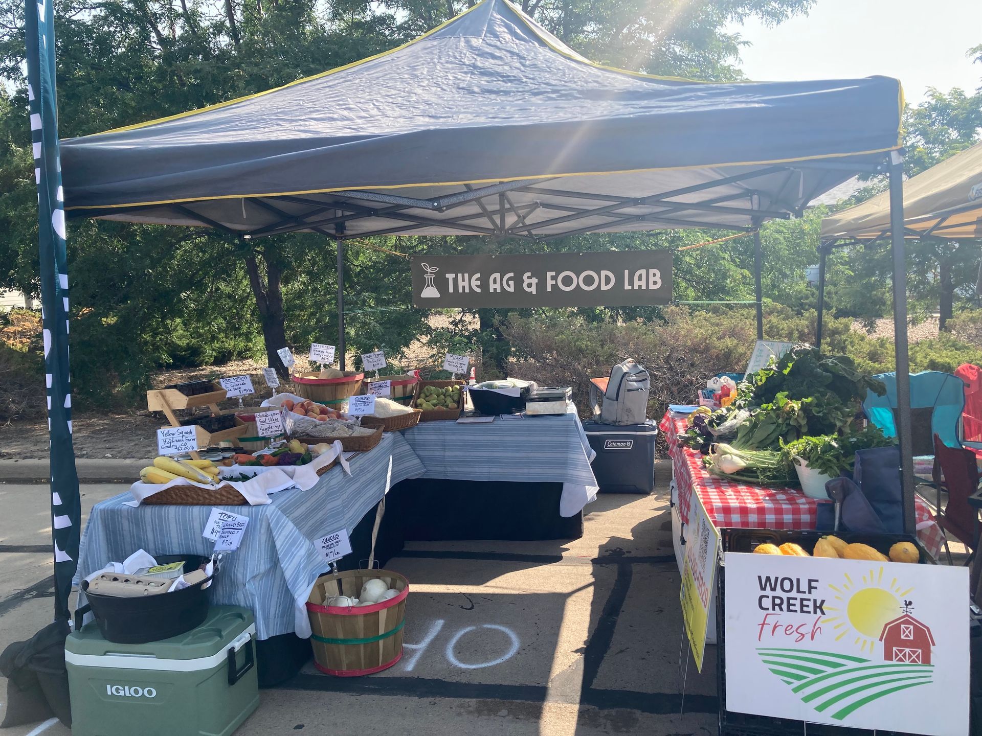 Farmers market stall with produce under a tent. 