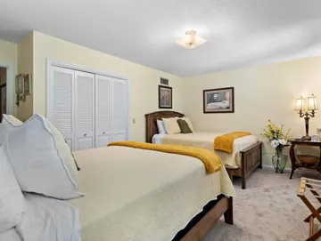 A bedroom with two beds , a desk and a lamp.