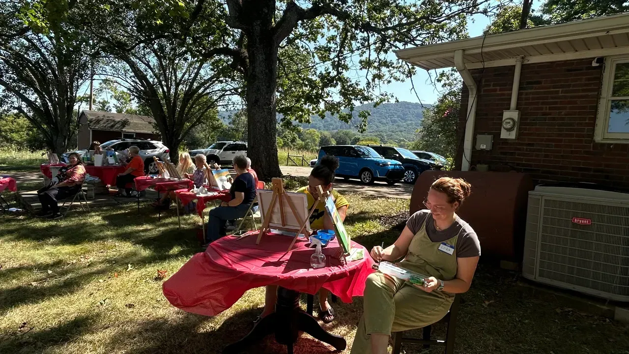 A woman is sitting at a table in front of a house.