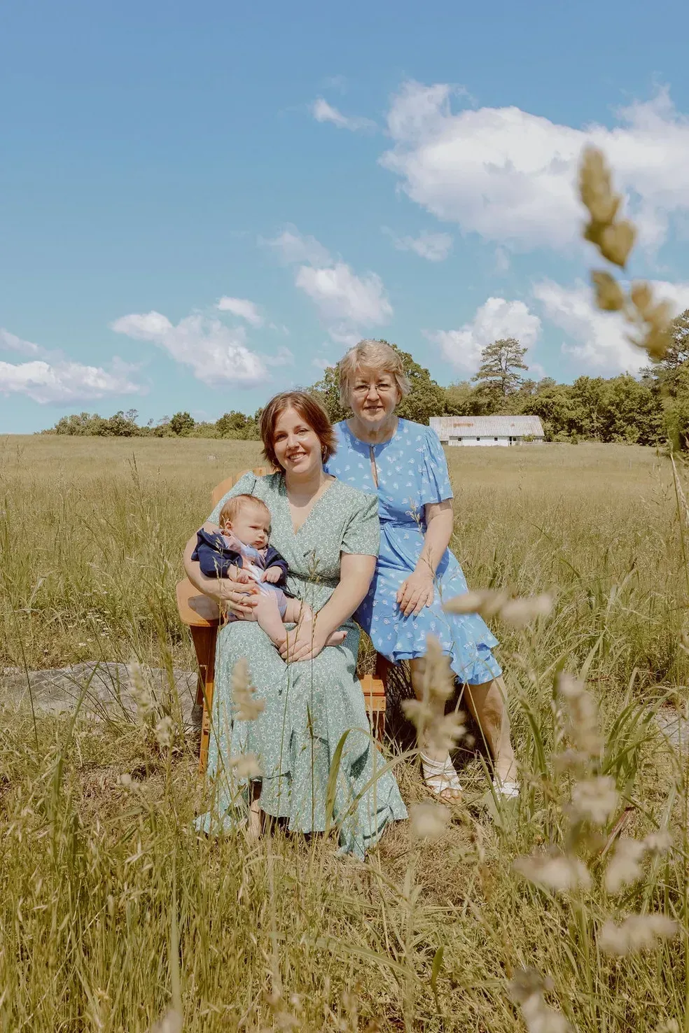 Two women and a baby are sitting in a field.